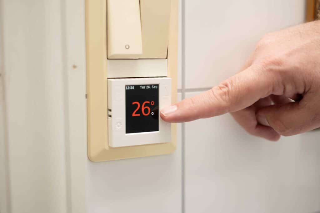 a finger pressing a temperature on a thermostat
