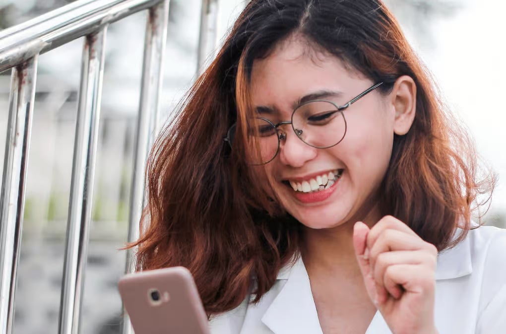 a woman smiling at a cell phone