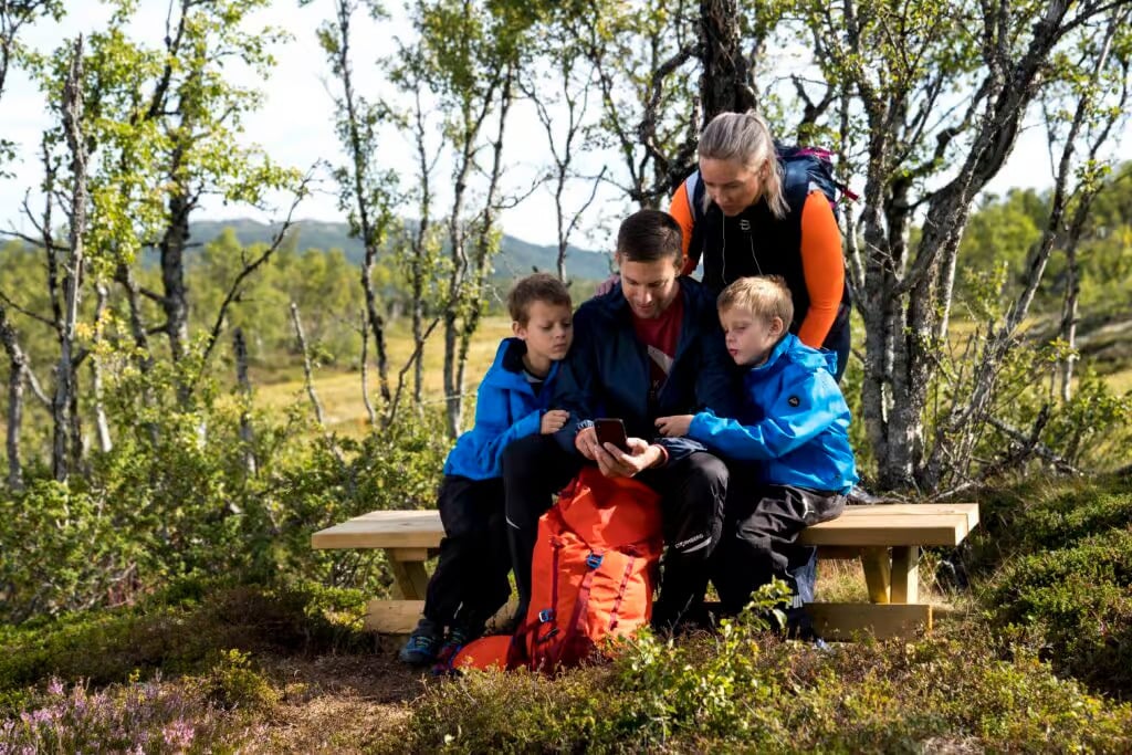 a man and two children sitting on a bench in the woods
