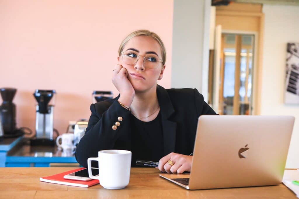a woman sitting at a table with a laptop and a cup